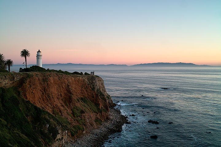 lighthouse on a bluff above the sea at sunset